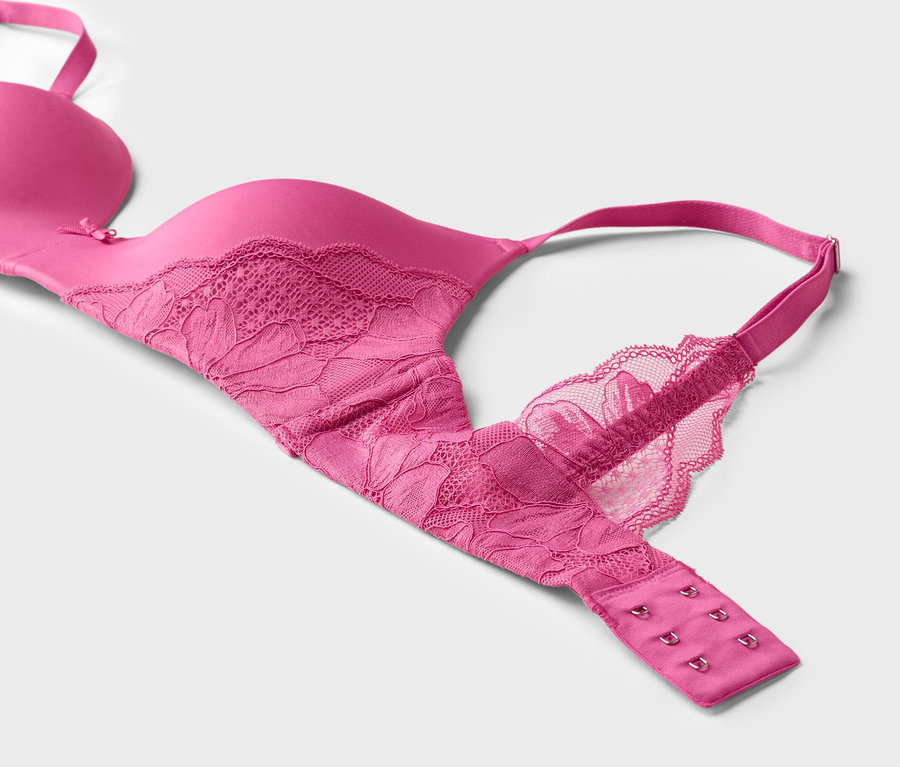 Nahaufnahme eines pinkfarbenen BHs mit Spitze auf weißem Hintergrund.