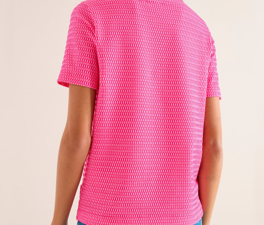 Frau von hinten in einem pinken, kurzärmeligen, strukturierten CECIL Sweatshirt und blauen Jeans.