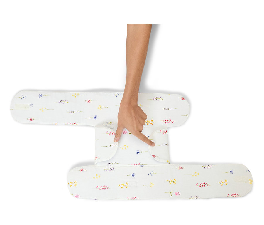 Hand berührt ein weißes Lagerungskissen mit Blumenmuster.