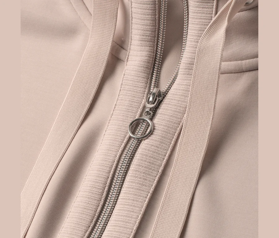 Nahaufnahme einer beigefarbenen Street One Sweatjacke mit silbernem Reißverschluss und Kordelzügen.