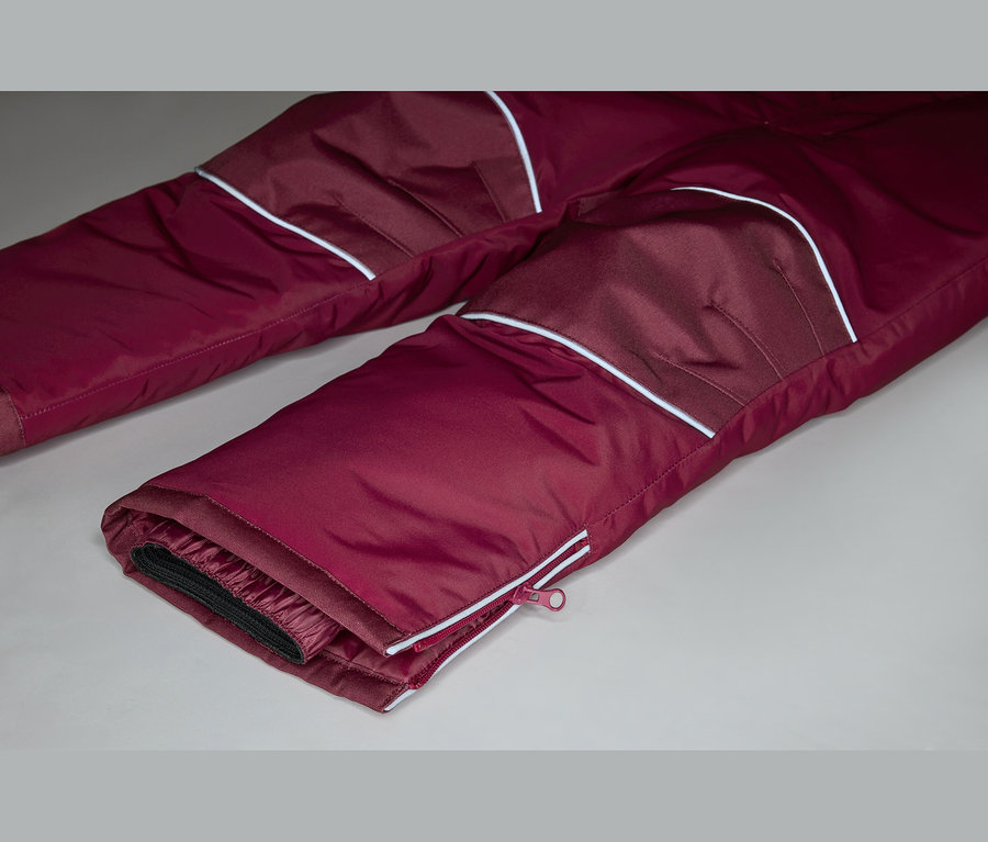 Nahaufnahme einer burgunderroten Hose mit weißen Akzenten und einem Reißverschluss am Bein.