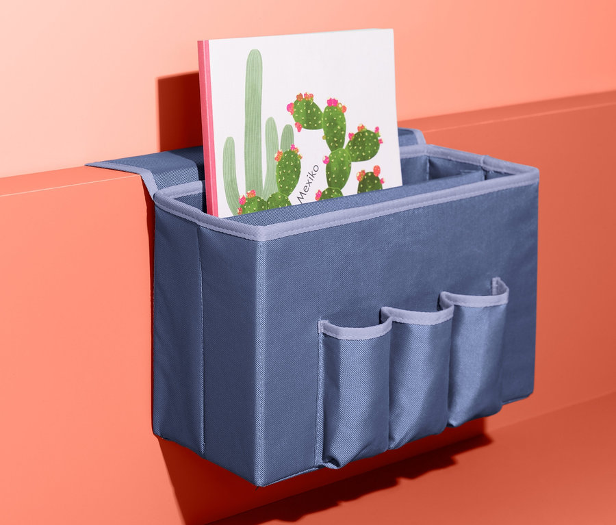 Blauer Bett-Ablagebox mit Taschen und einer Postkarte mit Kakteen.