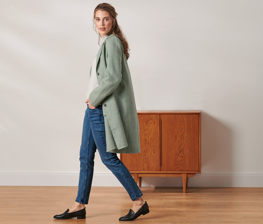 Frau geht, trägt einen kurzen Mantel mit Wolle.