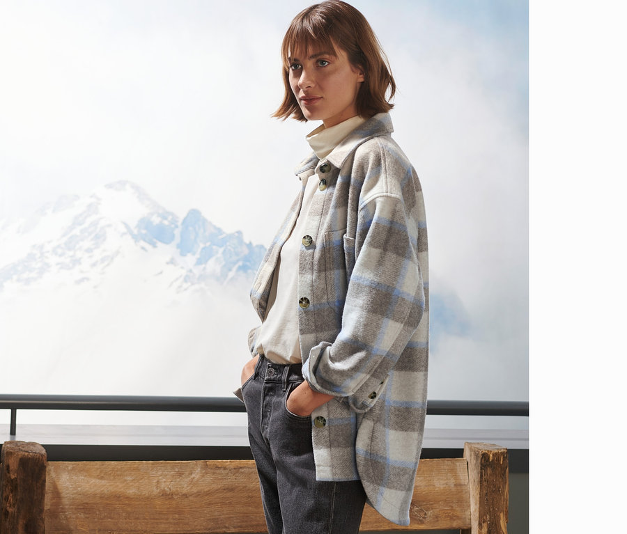 Frau trägt ein kariertes Overshirt und Jeans.