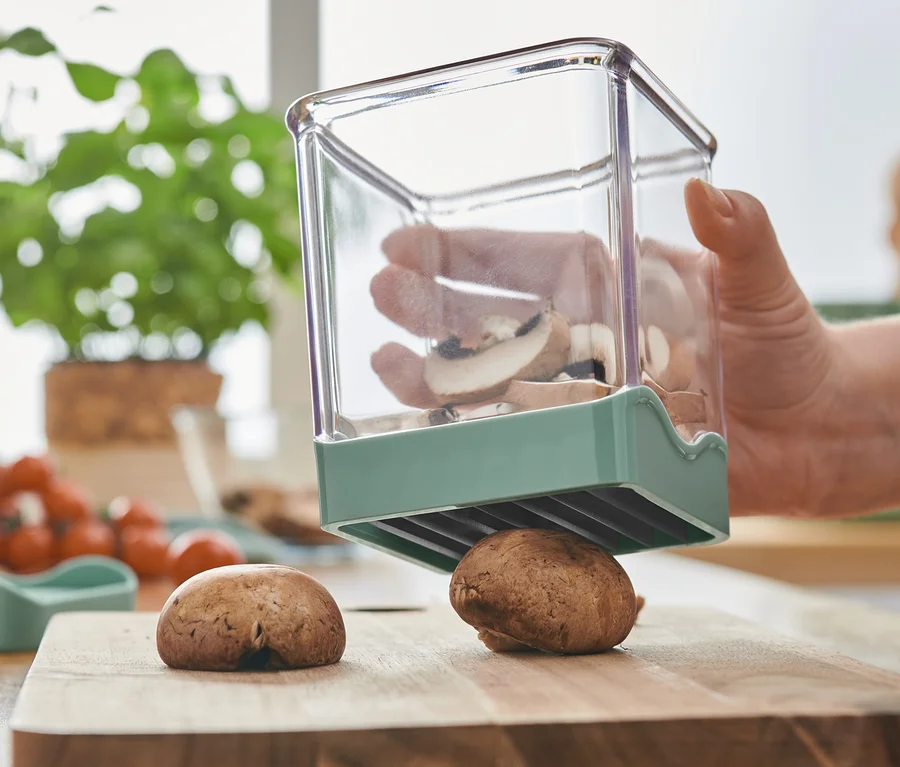 Frau schneidet Champignons mit einem Obst-und-Gemüseschneider.