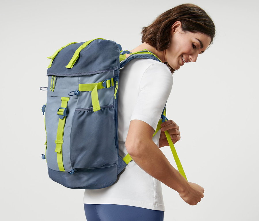 Frau justiert die Riemen eines Outdoor-Rucksacks.