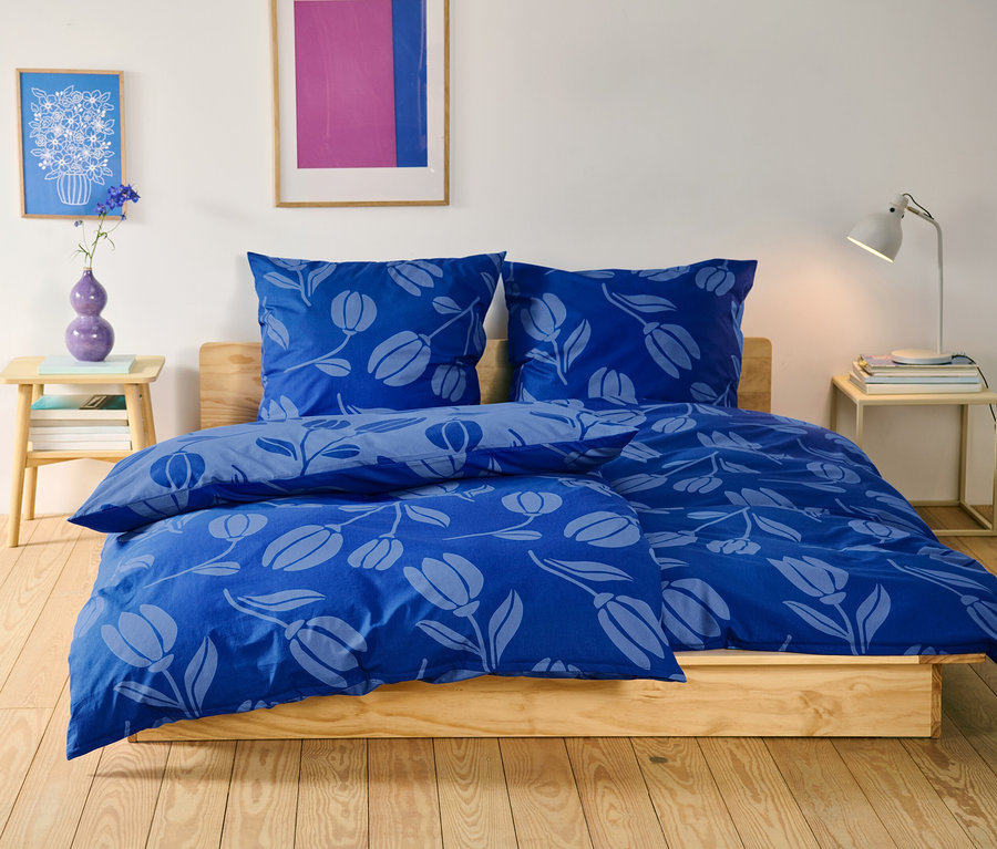 Floral gemusterte Renforcé-Bettwäsche in Normal- und Übergröße auf einem Bett.