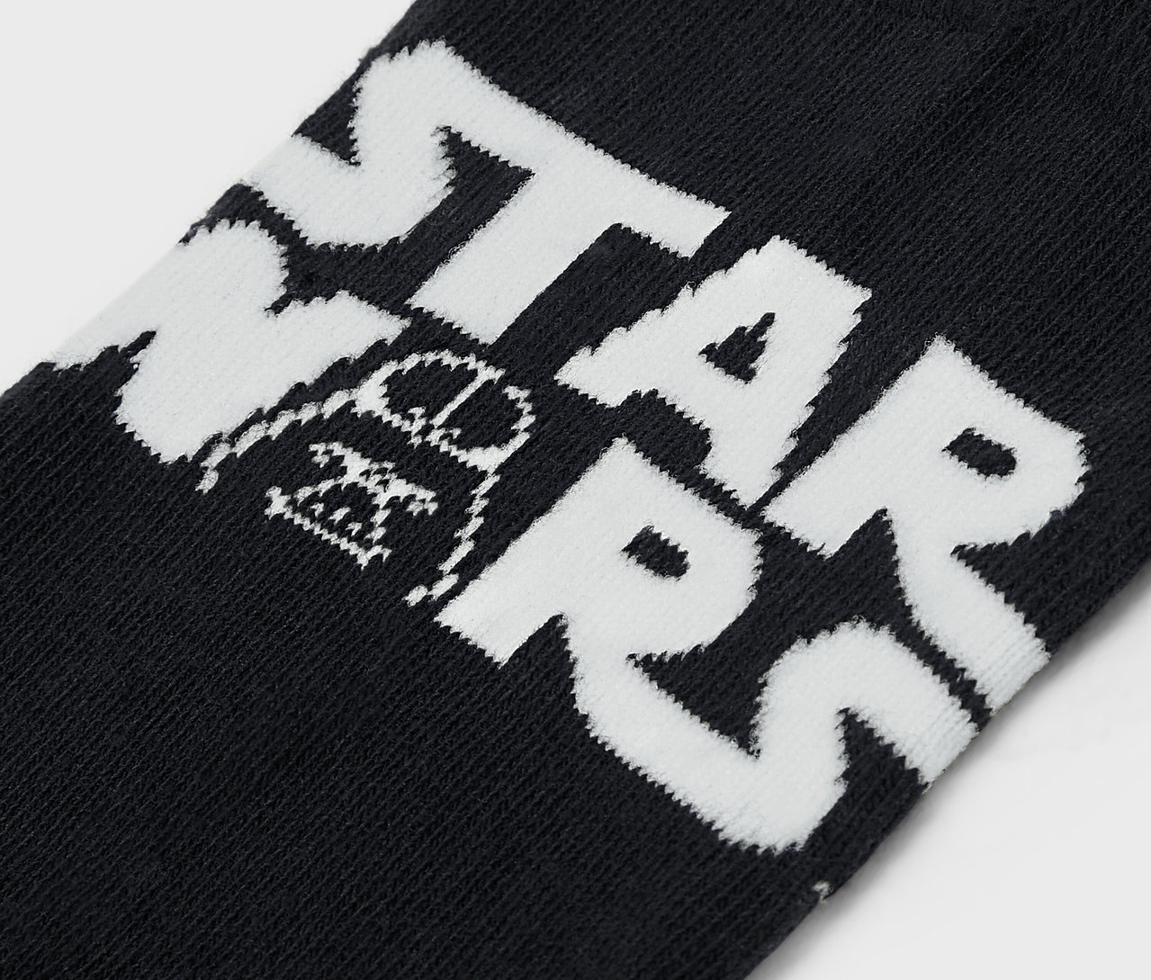 Detail einer schwarzen Socke mit dem weißen Schriftzug STAR WARS und einer Abbildung von Darth Vader.