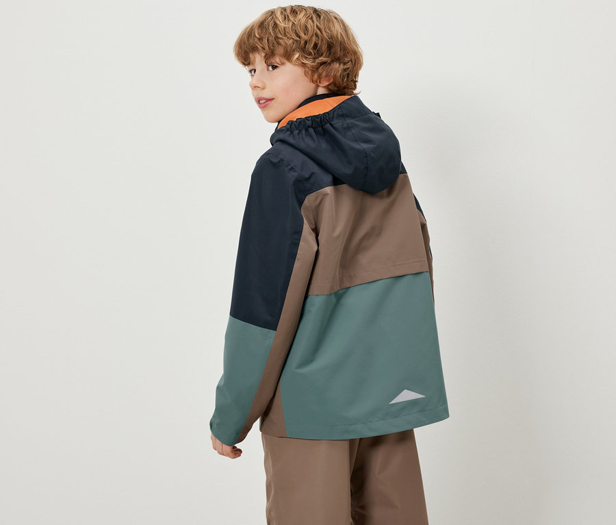 Ein Junge blickt über die Schulter und trägt eine farbige Kinder-Allwetterjacke.