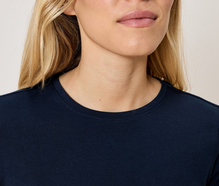 Oberkörper einer blonden Frau in einem marineblauen T-Shirt.