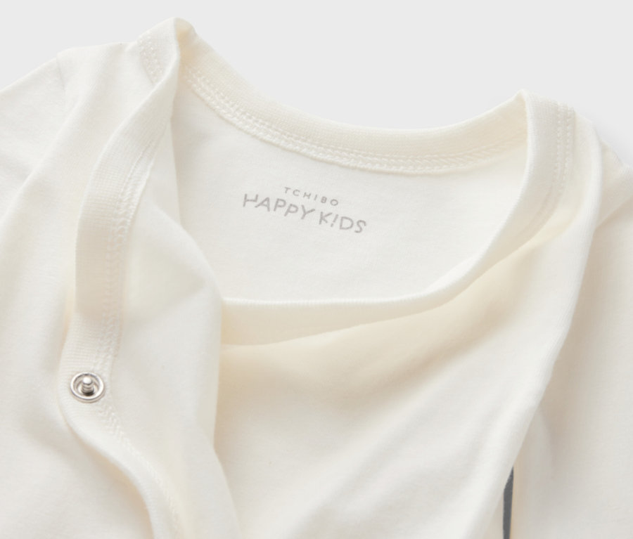 Detailansicht eines weißen 5er-Packs Baby-Bodys mit Mitwachsfunktion, mit Tchibo Happy Kids-Logo.