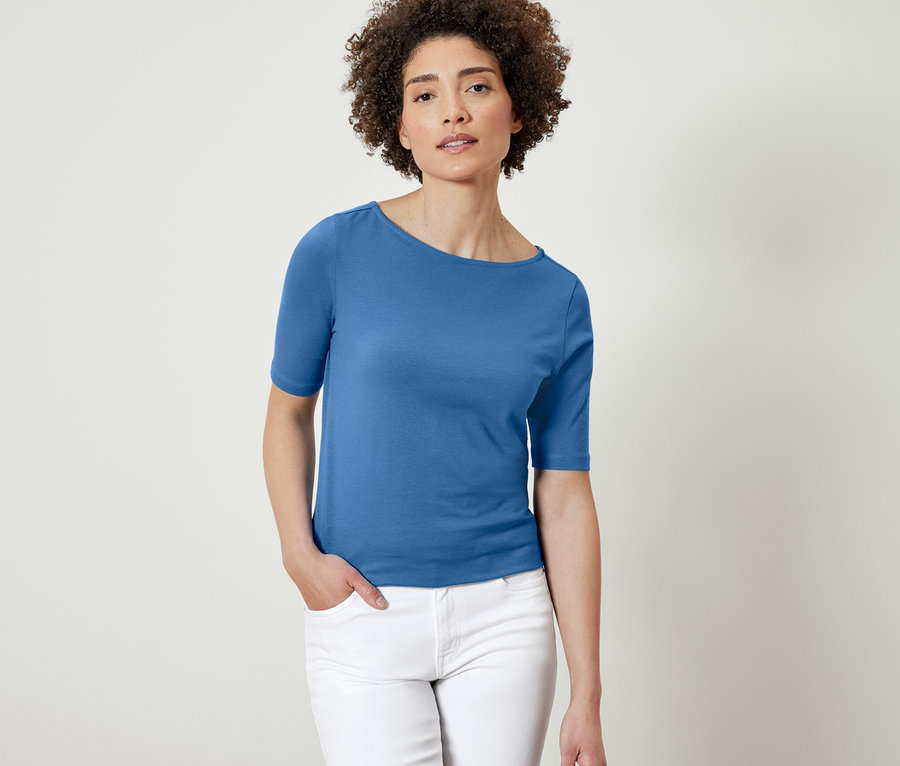 Frau posiert in blauem Halbarmshirt.