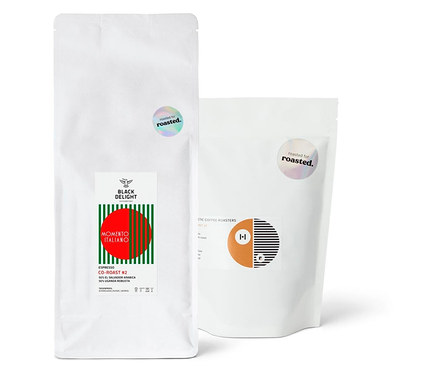 Zwei weiße Kaffeepackungen nebeneinander. Eine Packung ist Espresso Probierpaket "Co-Roast Duo".