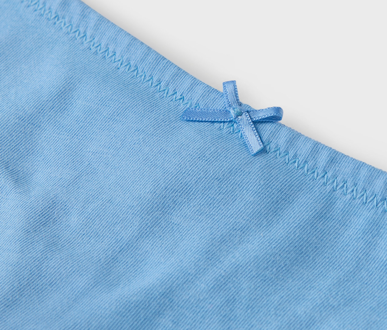Detailansicht einer hellblauen Unterhose mit Schleife.