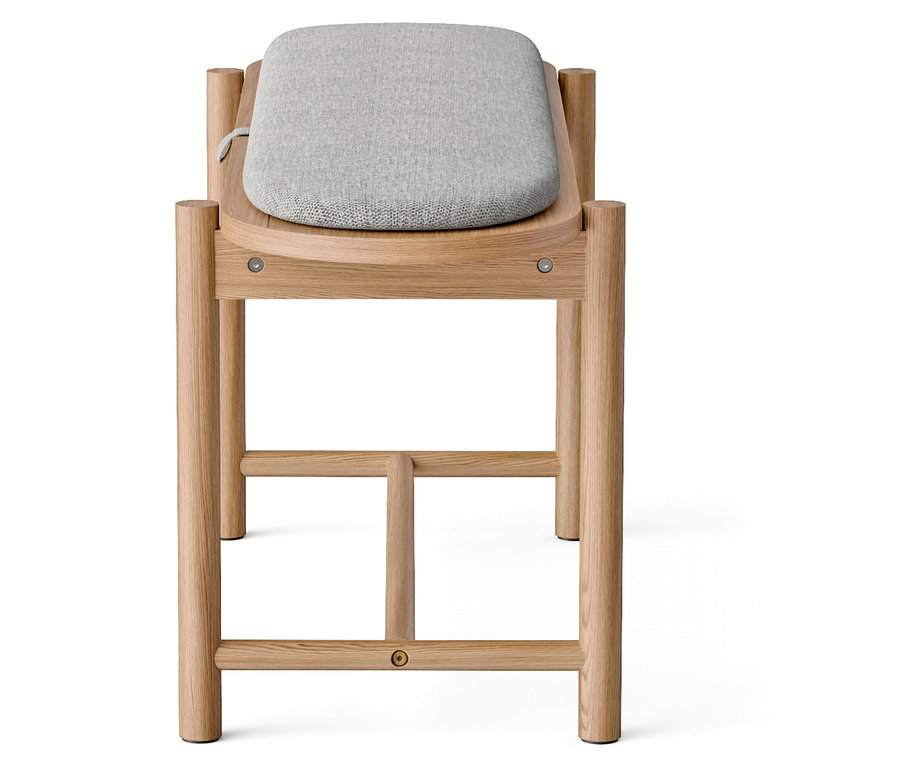 Detailaufnahme eines Holzschemels mit grauem Stoffbezug.