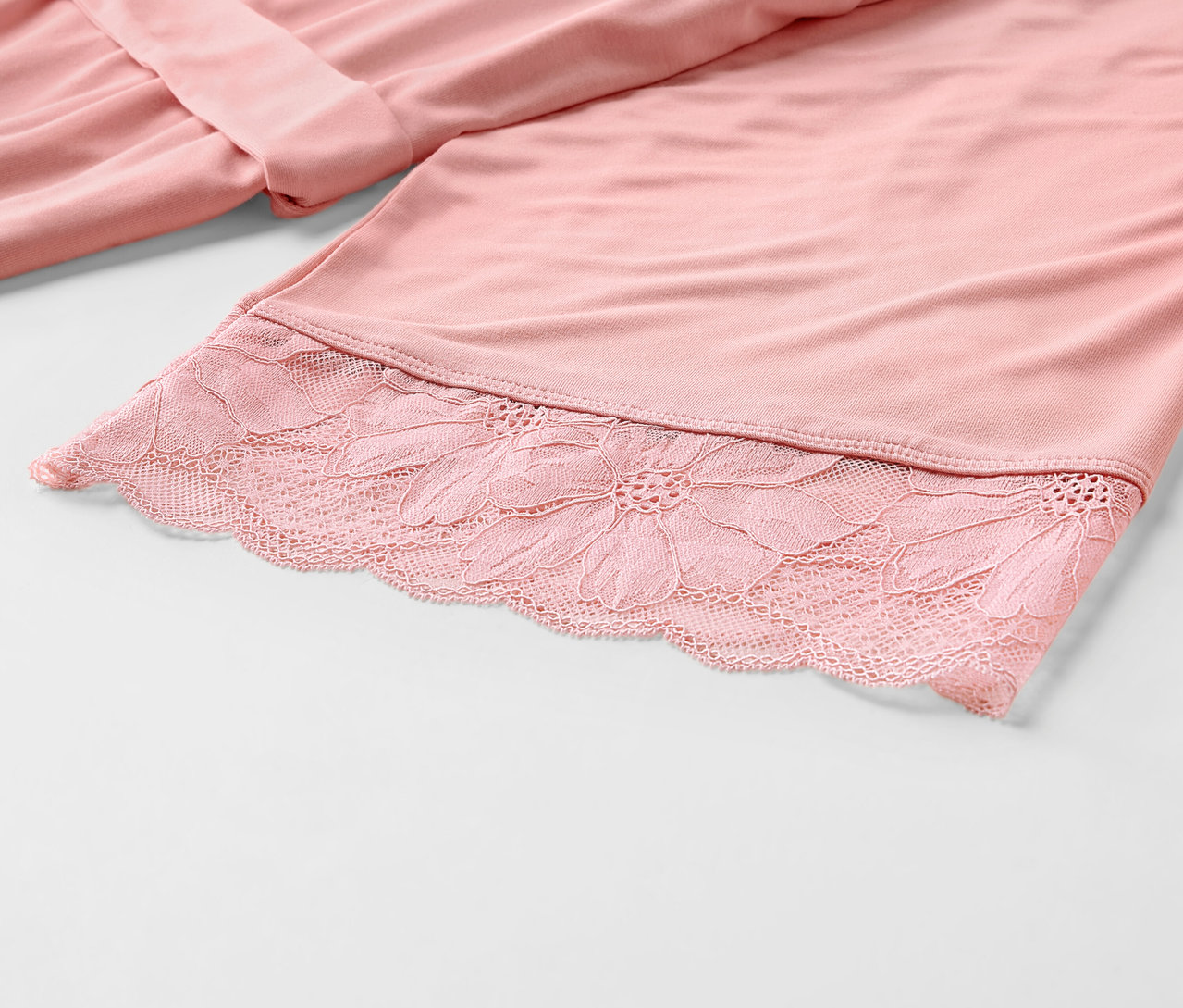 Detailansicht eines rosafarbenen Morgenmantels mit Spitze.