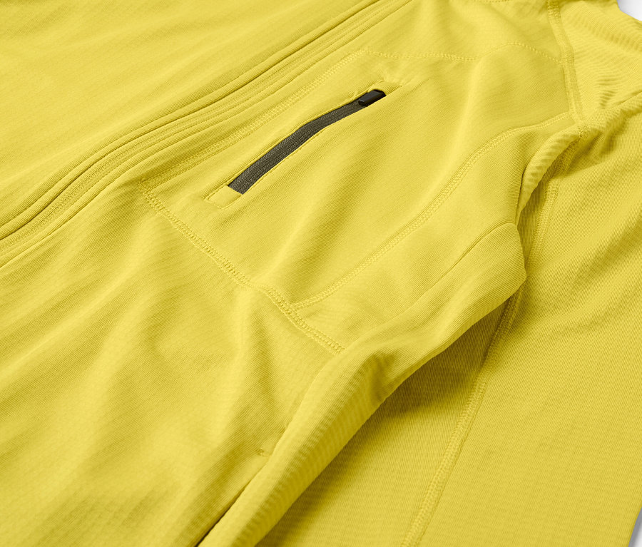 Detailaufnahme einer gelben Jacke mit Reißverschluss und Brusttasche.