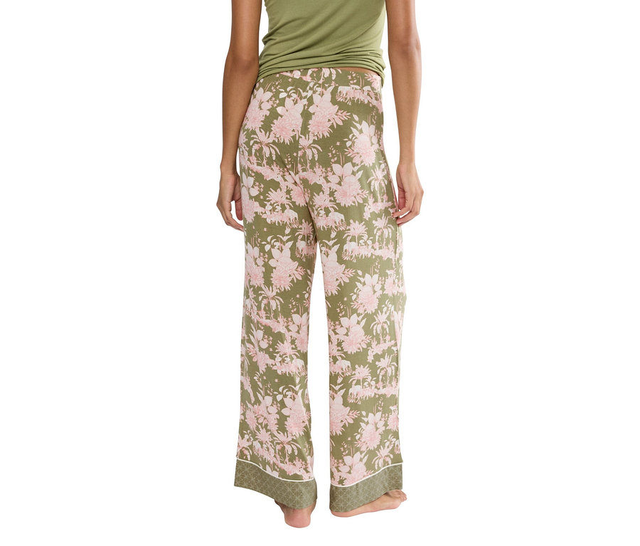 Rückansicht einer Frau, die eine grüne Hose mit rosa Blumenmuster und ein grünes Top trägt.