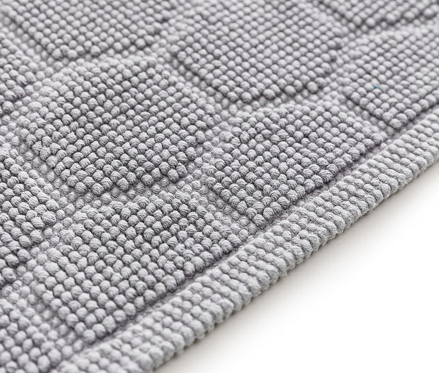 Nahaufnahme einer grauen Badematte mit erhabenem geometrischen Muster.