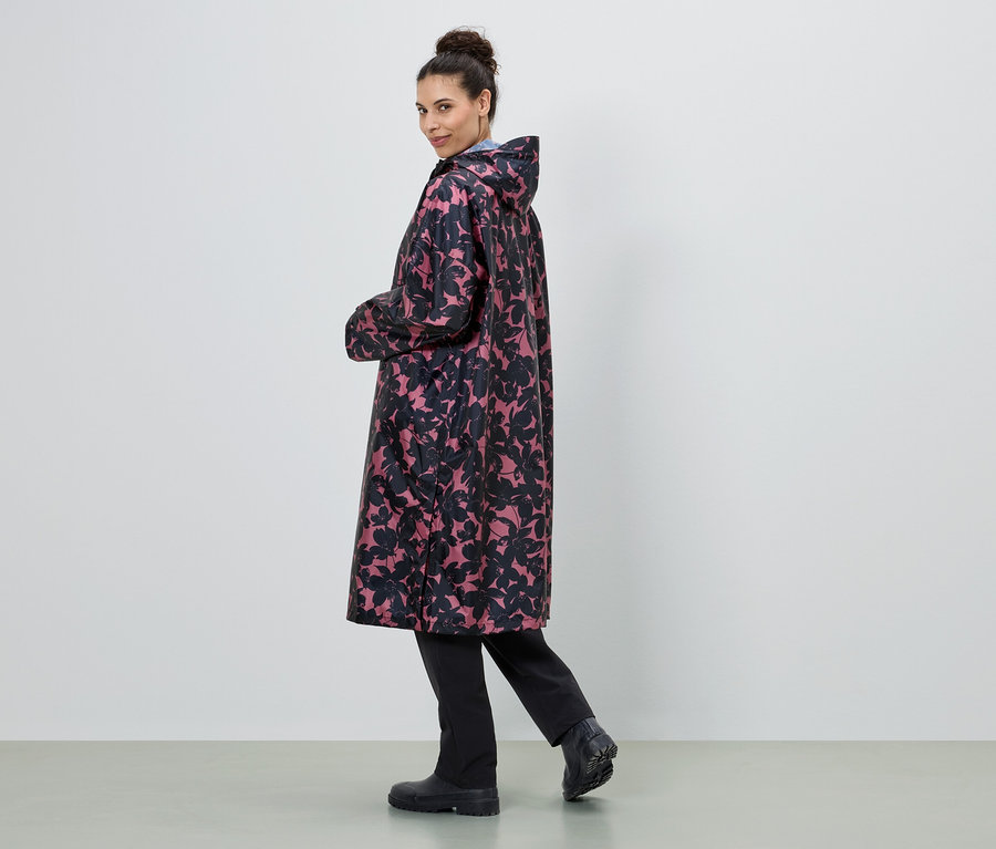 Frau trägt einen langen Regenmantel mit Blumenmuster in Schwarz und Pink.