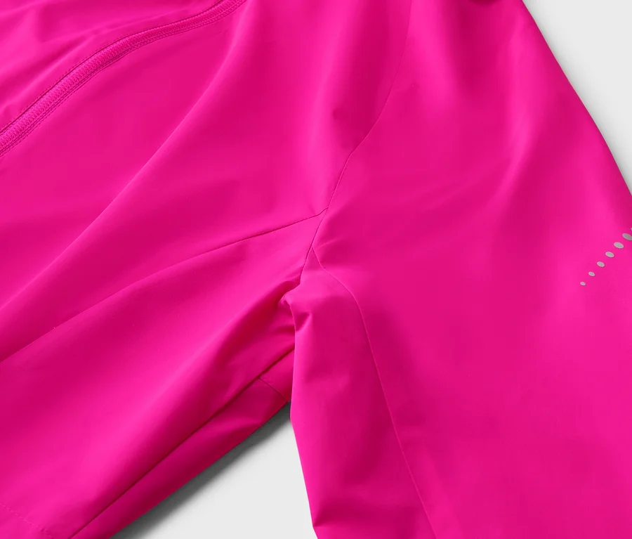 Nahaufnahme einer pinkfarbenen Jacke mit Reißverschluss und reflektierenden Punkten am Ärmel.