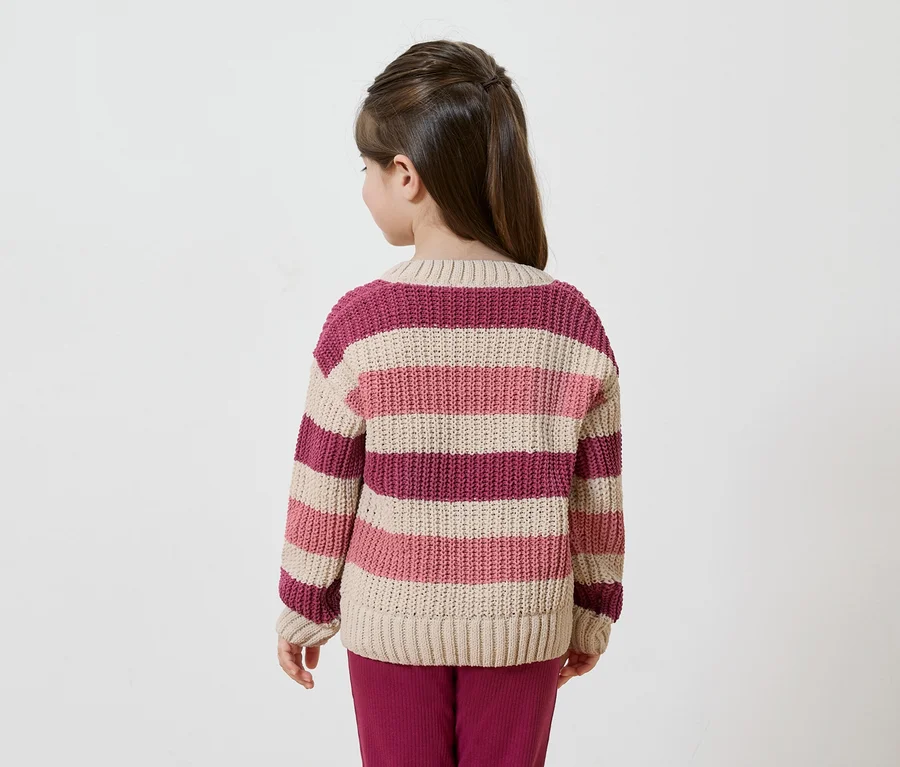 Rückansicht eines Mädchens mit hochgesteckten Haaren, das einen gestreiften Pullover in Beige-, Rosa- und Burgundertönen und eine Hose trägt.