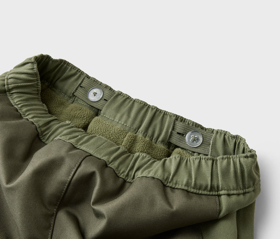 Nahaufnahme einer olivgrünen Hose mit verstellbarem Bund und Fleece-Futter.