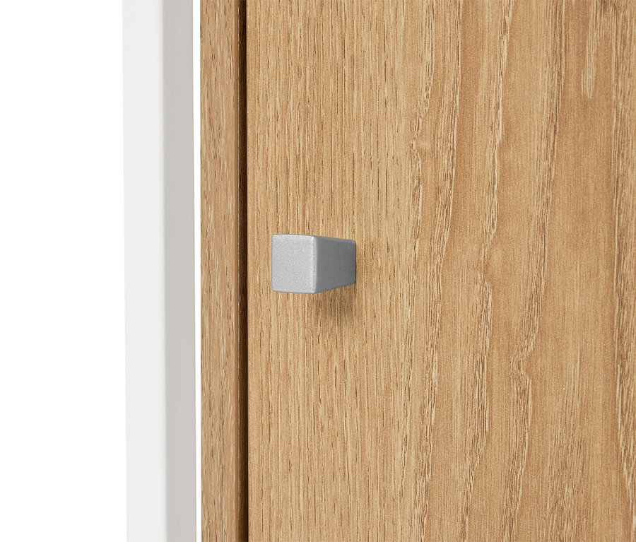 Nahaufnahme einer Schranktür aus hellem Holz mit einem silbernen, quaderförmigen Griff.