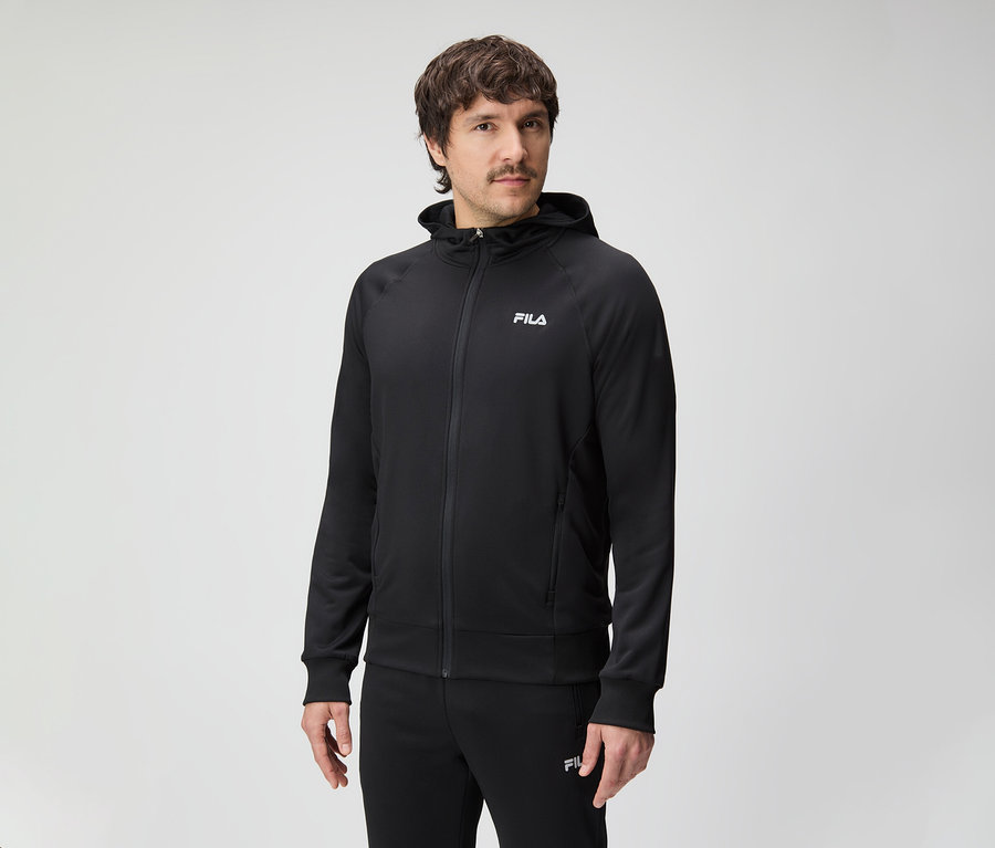 Mann mit Schnurrbart trägt einen schwarzen Fila-Trainingsanzug mit Kapuze.