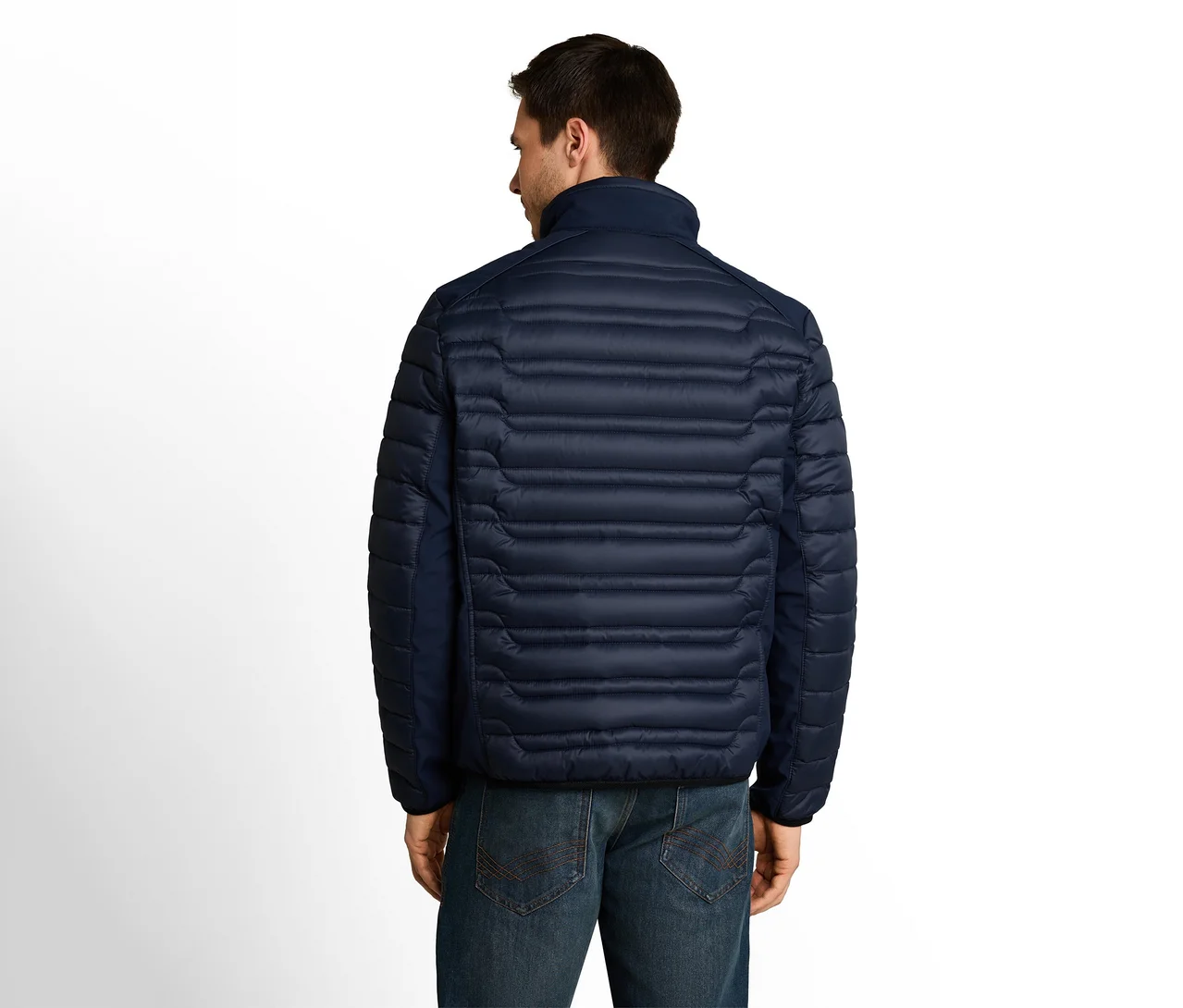 Mann von hinten in einer dunkelblauen Steppjacke und Jeans vor weißem Hintergrund.