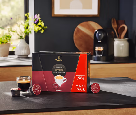 Schwarze Cafissimo pure+ und eine Packung Cafissimo Espresso kräftig - 96 Kapseln auf einer Küchentheke.