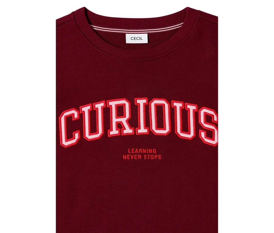 Bordeauxrotes CECIL Sweatshirt mit großem, rot-weiß gesticktem Schriftzug „CURIOUS“ und darunter „LEARNING NEVER STOPS“.
