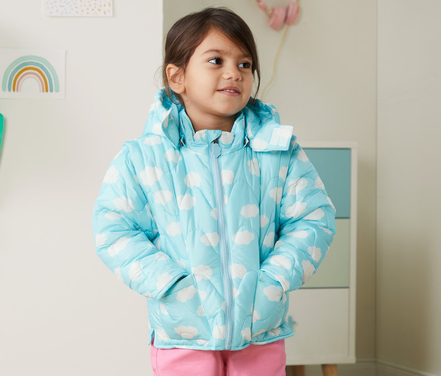 Mädchen mit Steppjacke aus recyceltem Material mit Händen in den Taschen.