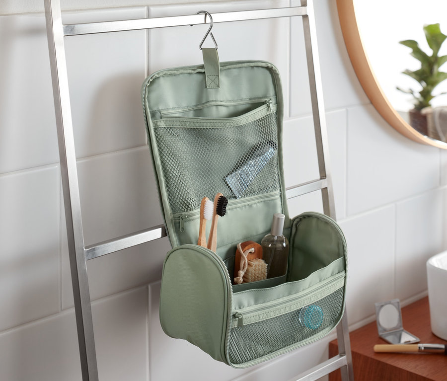 Eine grüne Kulturtasche hängt an einer Leiter im Badezimmer.