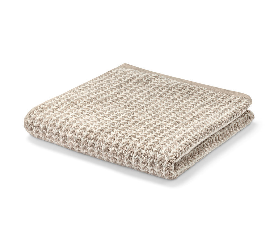 Ein gefaltetes Premium-Badetuch in Beige auf einem weißen Hintergrund.