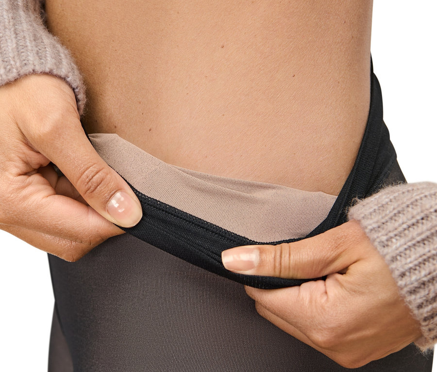 Frau hält 50-DEN-Feinstrumpfhose in transparenter Optik am Bund.