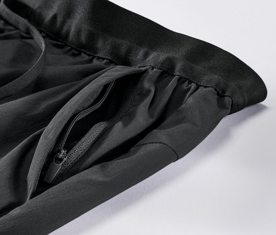 Detailaufnahme einer schwarzen Funktionshose mit Reißverschlusstasche.