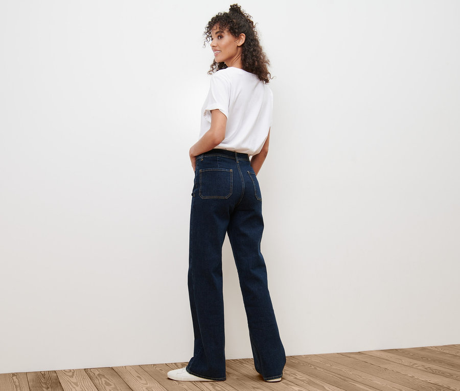 Eine Frau blickt über ihre Schulter und trägt eine Flared Jeans – Fit »Cara« und ein weißes T-Shirt.