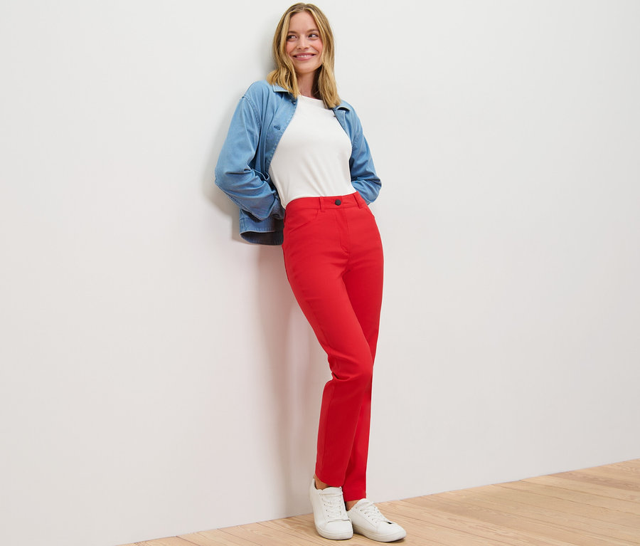 Frau posiert in roter Bengalin-Hose, weißem T-Shirt und blauer Jacke.