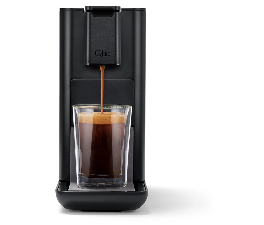 Kaffee fließt aus der Qbo ICONIC Dark Chrome Kaffeemaschine in ein Glas.