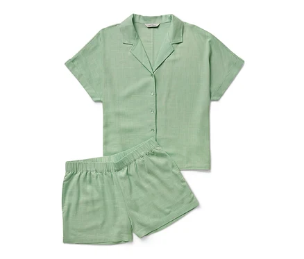 Ein grünes Shorty-Pyjama-Set liegt auf einem weißen Hintergrund.