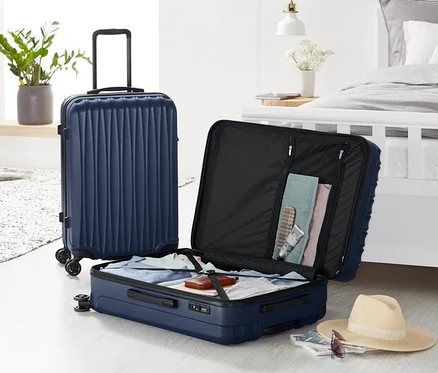 Zwei Hartschalen Koffer-Sets: ein großer steht, ein kleiner ist geöffnet und mit Kleidung gefüllt.