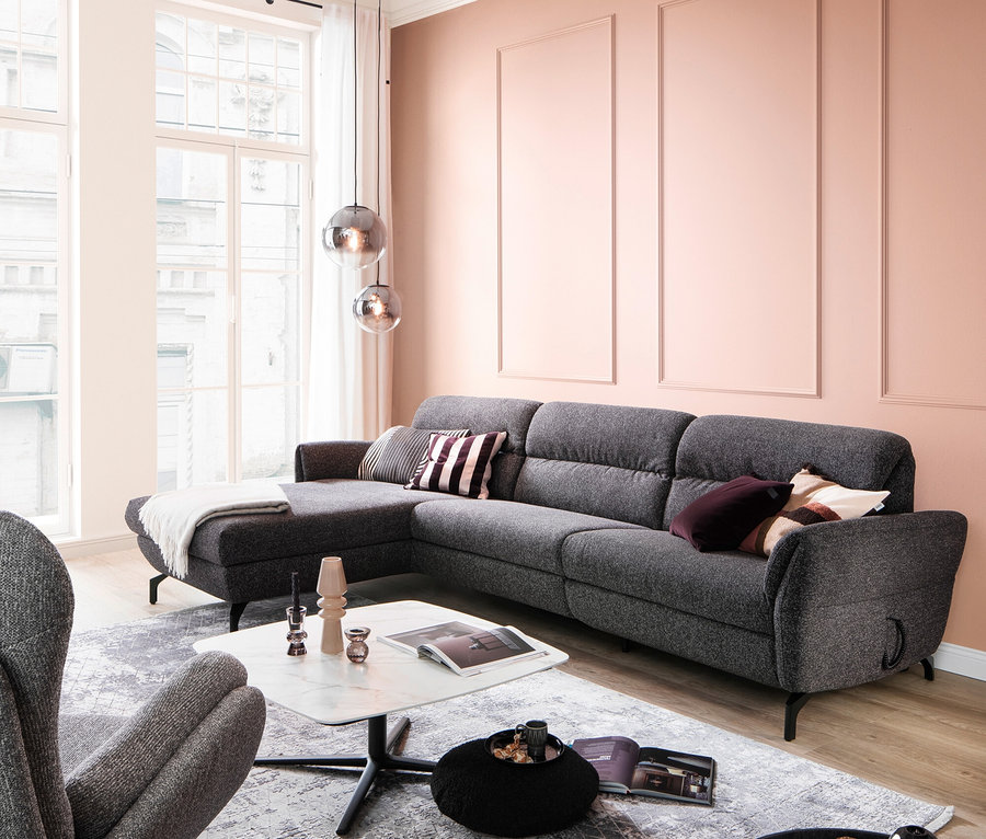 Wohnzimmer mit grauem Ecksofa, weißem Teppich und Couchtischen.