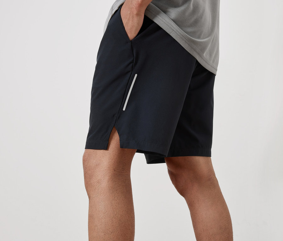 Mann mit Hand in der Tasche einer schwarzen Sportshorts.