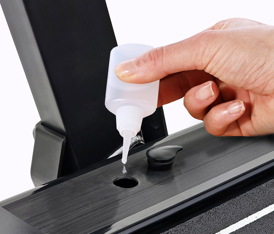 Hand tropft Öl auf ein Laufband 2 in 1.