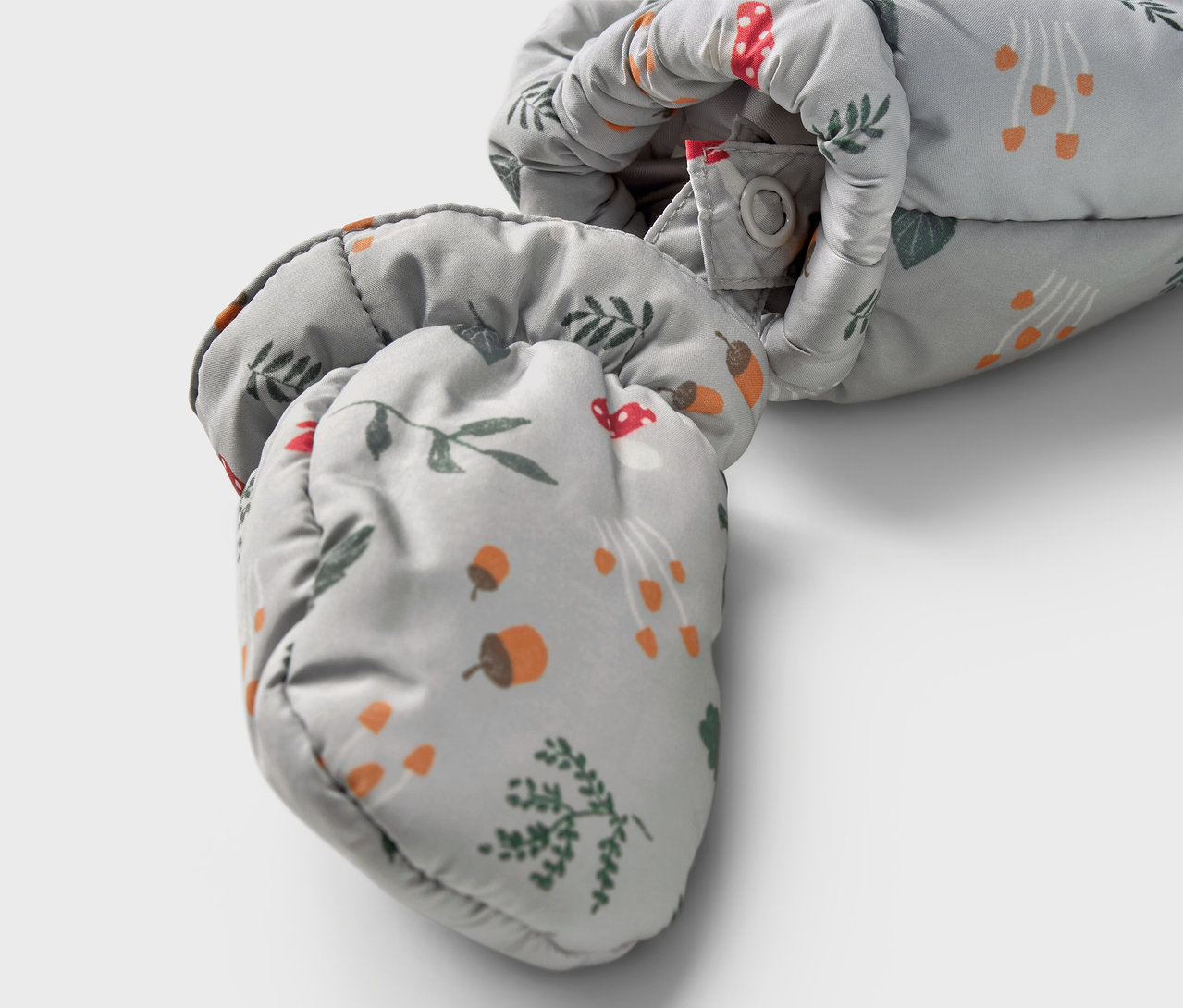 Detailansicht eines Baby-Winteroveralls mit Pilz-, Eichel- und Zweig-Muster.