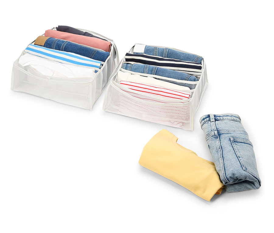 Zwei weiße Organizer gefüllt mit Kleidung und gefaltete Jeans und ein gelbes Sweatshirt auf weißem Hintergrund.