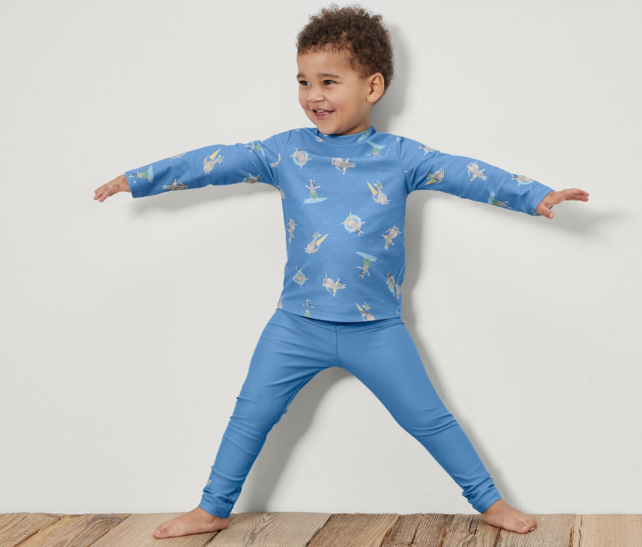 Ein Junge steht mit ausgestreckten Armen und trägt Kinder-Badeleggings mit UV-Schutzfaktor 80.