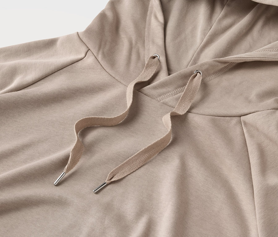 Detailansicht eines beigen Kapuzenpullovers mit Kordelzug.