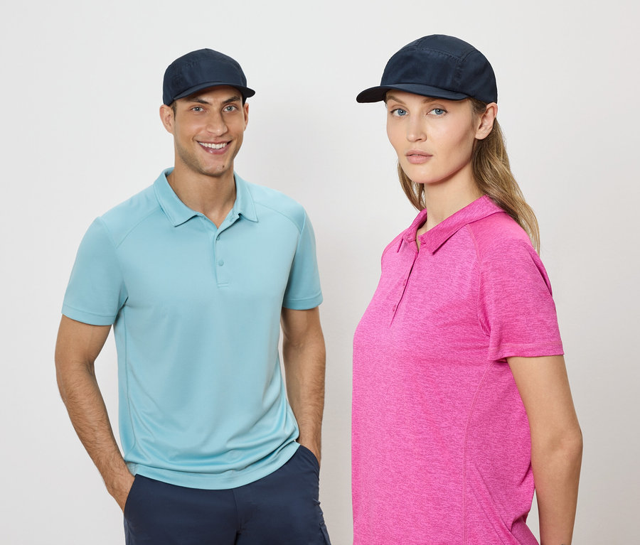 Ein Mann und eine Frau stehen nebeneinander und tragen blaue Kappen und Poloshirts vor einem neutralen Hintergrund.